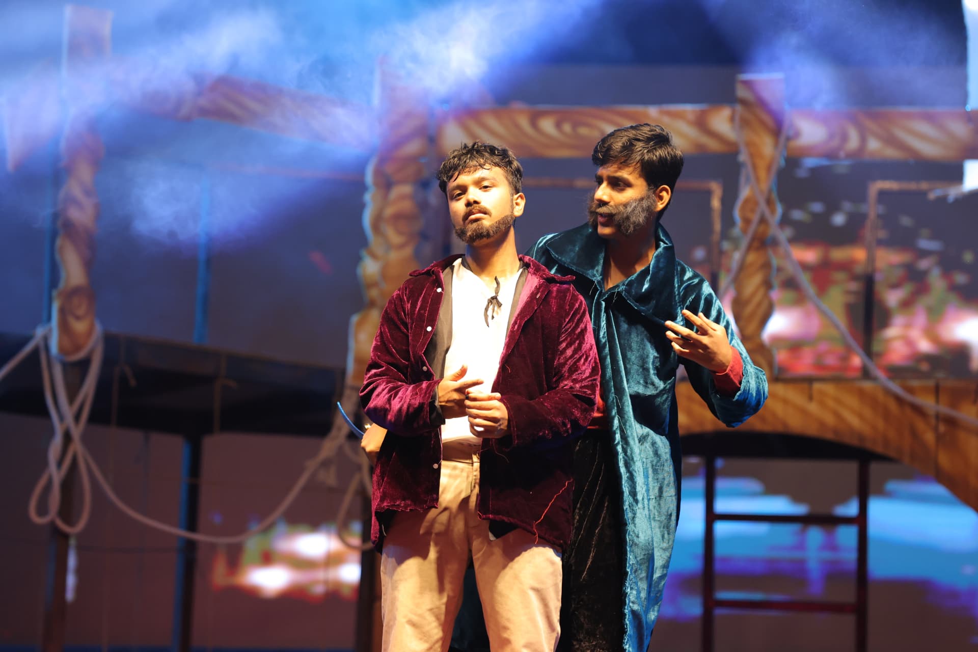 Dramatic two-character scene in velvet costumes under blue light